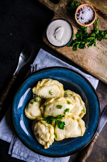 Ukrainian vareniki potato dumplings with chive garnish and sour cream — Stock Photo