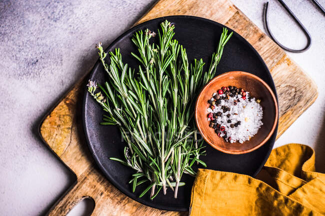 Fresh rosemary with sea salt and peppercorns on a plate — Stock Photo