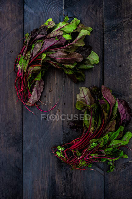 Свежие органические свекловичные листья на деревянном столе в качестве здоровой концепции приготовления пищи — стоковое фото