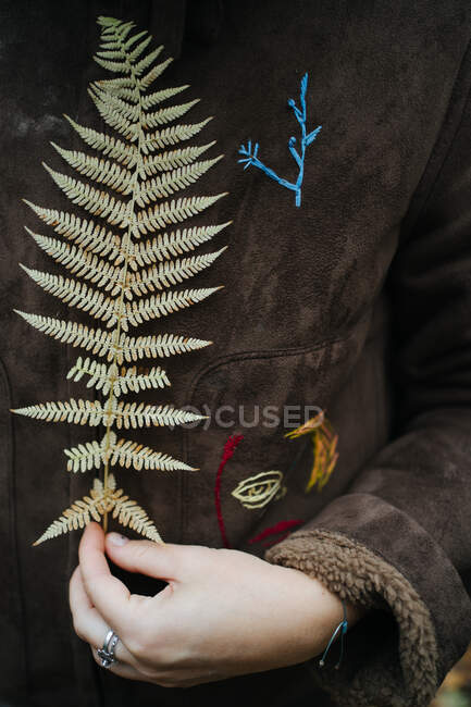 Primo piano di una donna che tiene una fronda di felce davanti alla giacca, Russia — Foto stock