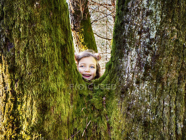 Menina sorridente escondida atrás de uma árvore, Itália — Fotografia de Stock