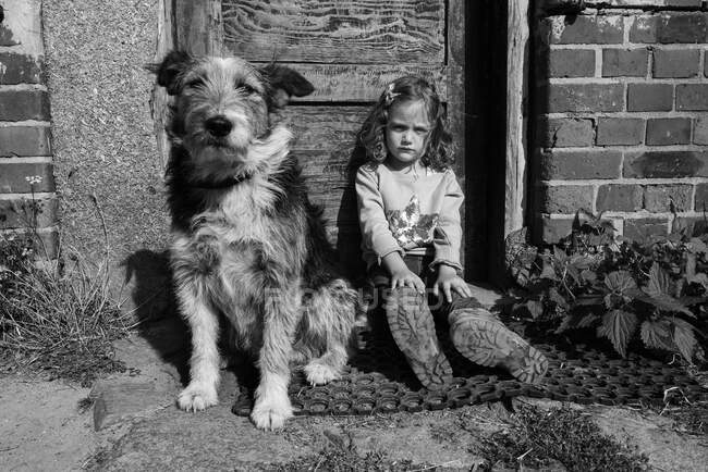 Mädchen sitzt mit ihrem Hund vor der Haustür, Polen — Stockfoto