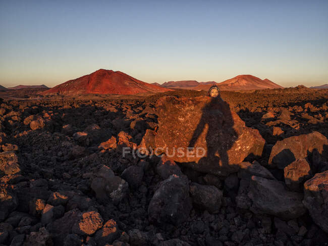 Юмористическое фото девушки, заглядывающей на вершину скал, Лансароте, Канарские острова, Испания — стоковое фото