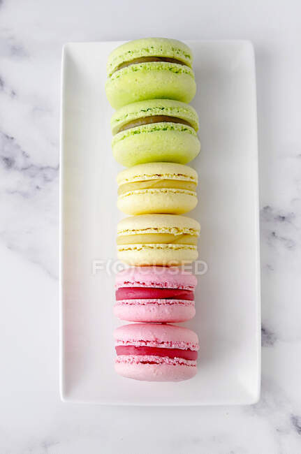 Plate of strawberry, pistachio and lemon macaroons — Stock Photo