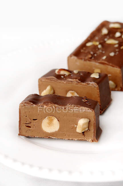 Schokolade, Haselnuss- und Nougatscheiben auf einem Teller — Stockfoto