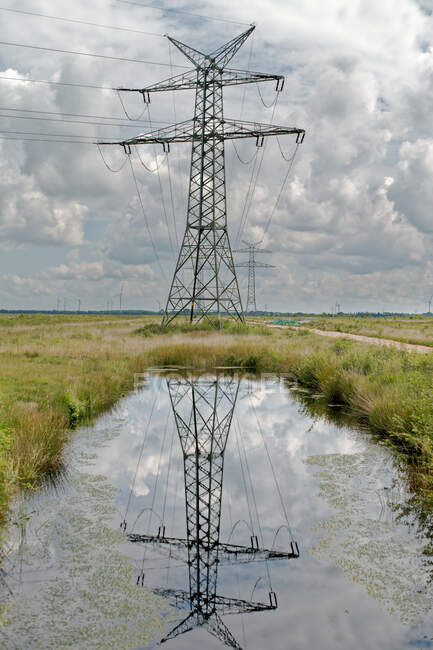 Linea elettrica ad alta tensione riflessa in uno stagno nel paesaggio rurale, Bassa Sassonia, Germania — Foto stock