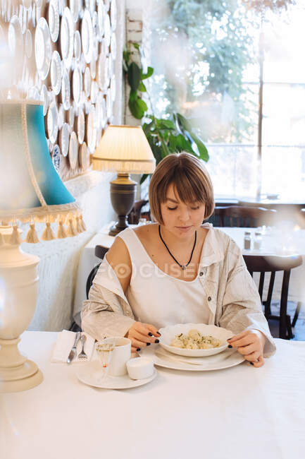 Frau sitzt in Restaurant und isst Knödel — Stockfoto