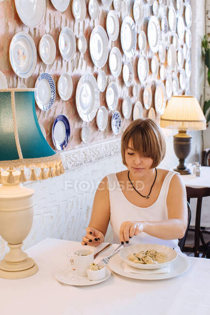 Mulher sentada em um restaurante comendo bolinhos — Fotografia de Stock