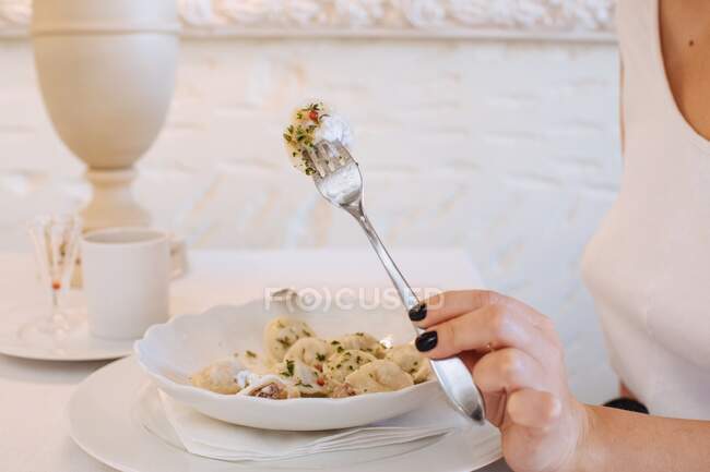 Женщина сидит в ресторане и ест пельмени — стоковое фото