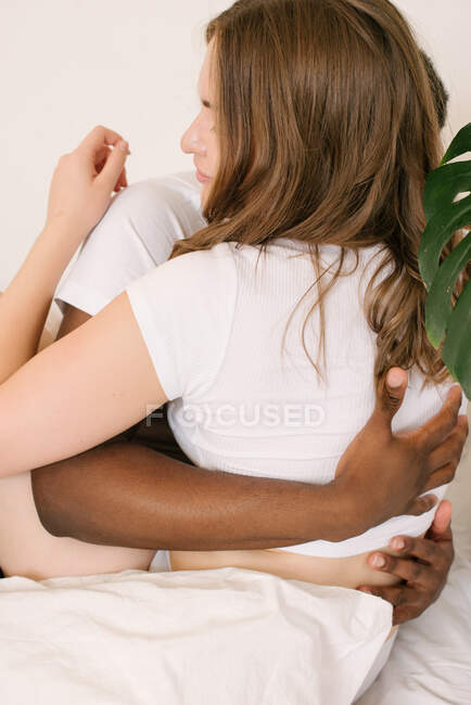 Mixed race couple sitting in bed hugging in the morning — Stock Photo