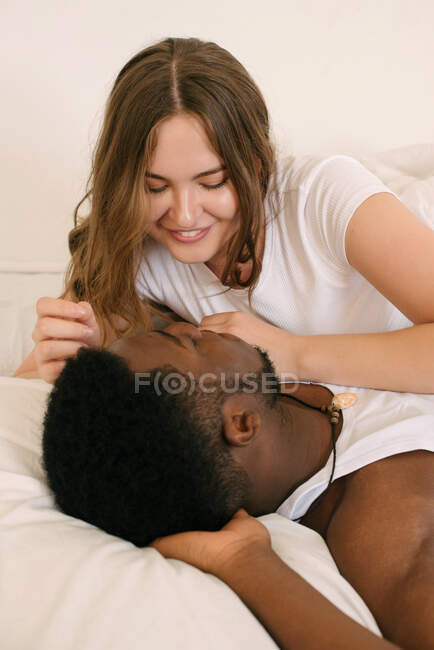 Смешанная расовая пара, лежащая в постели и говорящая утром — стоковое фото