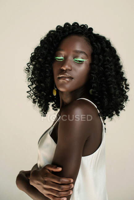 Retrato de uma bela menina africana com verde compõem olhando por cima de seu ombro — Fotografia de Stock