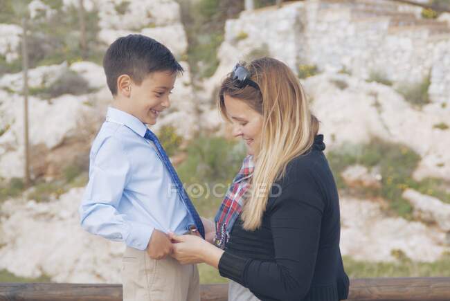Sorridente madre rimboccando la camicia di suo figlio — Foto stock