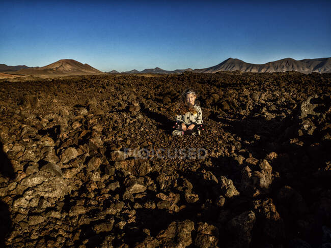 Fille assise dans un champ de lave, Lanzarote, Îles Canaries, Espagne — Photo de stock