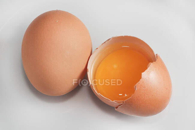 Свежее яйцо рядом с разбитым яйцом — стоковое фото