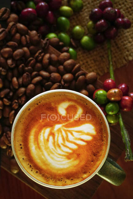Overhead view of a cappuccino with raw and roasted coffee beans — Stock Photo
