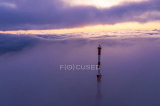 Torre de comunicaciones que se eleva a través de una alfombra de nubes al amanecer, Salzburgo, Austria - foto de stock