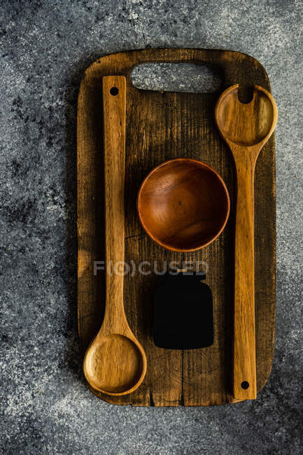 Colheres de madeira e uma tigela em uma tábua de cortar — Fotografia de Stock