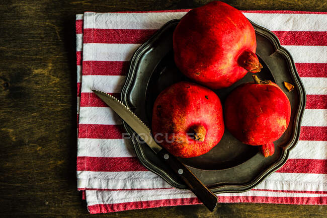 Three organic pomegranates on a plate — Stock Photo