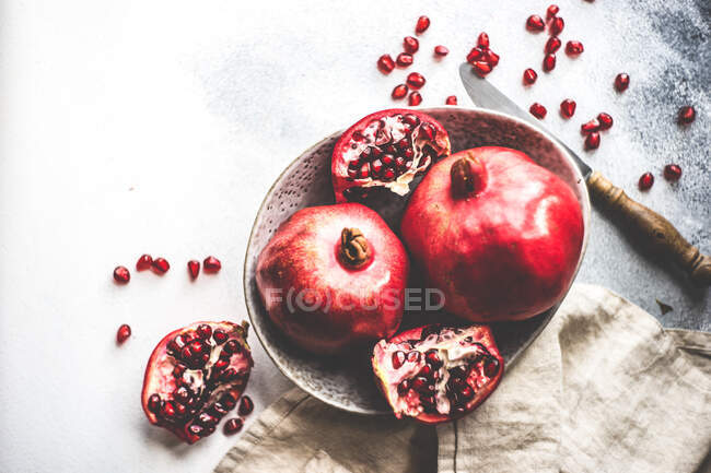 Organic pomegranate fruits with its seeds on plate on stone grey background as a organic food concept — Stock Photo