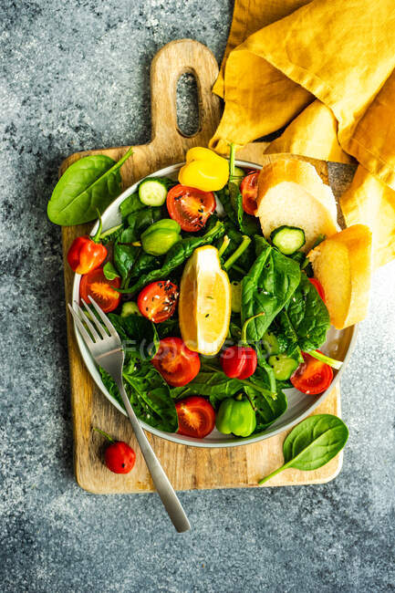 Conceito de alimento saudável com folhas de espinafre orgânico fresco e salada de legumes em fundo rústico com espaço de cópia — Fotografia de Stock