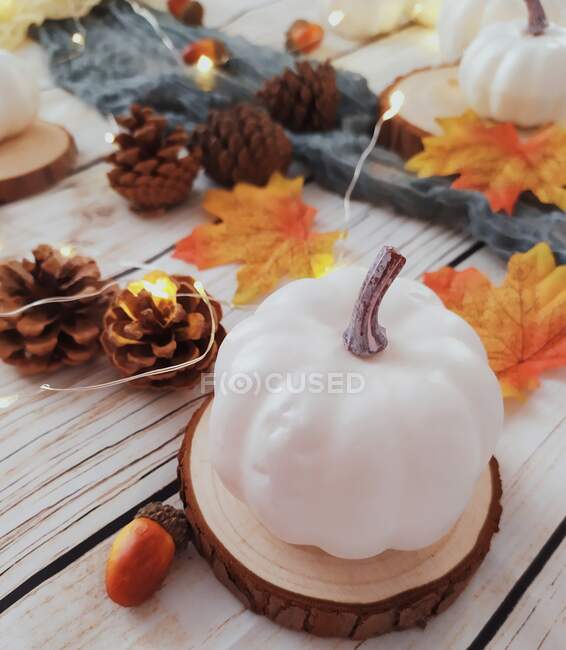 Abóbora, cone de pinheiro, folhas de outono e exposição de luz de fada em uma mesa — Fotografia de Stock