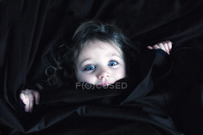 Retrato de uma menina sorridente escondida sob lençóis — Fotografia de Stock