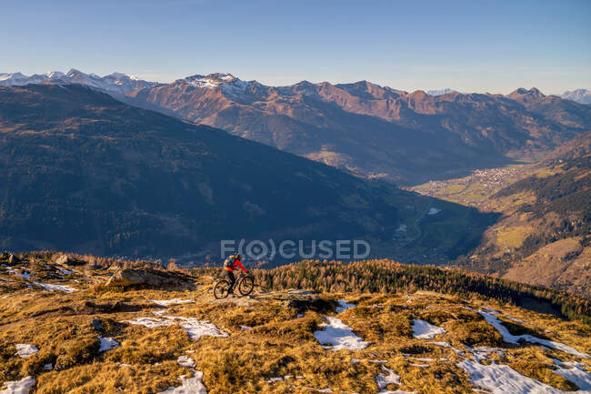 Woman mountain biking in alpine landscape in late autumn snow, Gastein, Salzburg, Austria — Stock Photo