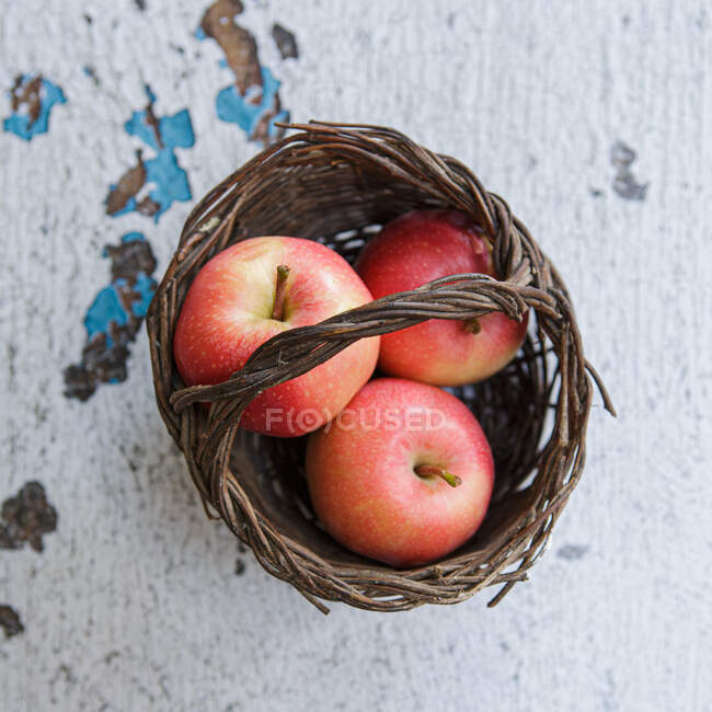 Overhead view of three apples in a basket — Stock Photo