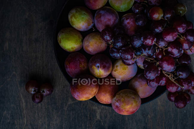 Blick von oben auf frische Pflaumen und Trauben auf einem Tisch — Stockfoto