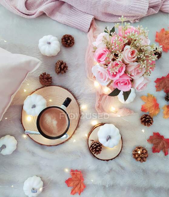 Vista aérea de una taza de café, flores, calabazas, ropa y luces de hadas - foto de stock