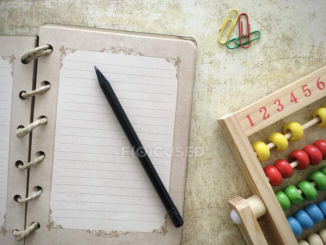 Visão aérea de um caderno aberto com lápis ao lado de um ábaco — Fotografia de Stock
