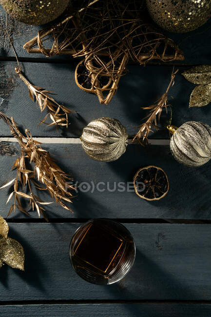 Verre de whisky avec un bâton de cannelle et des décorations de Noël en or — Photo de stock