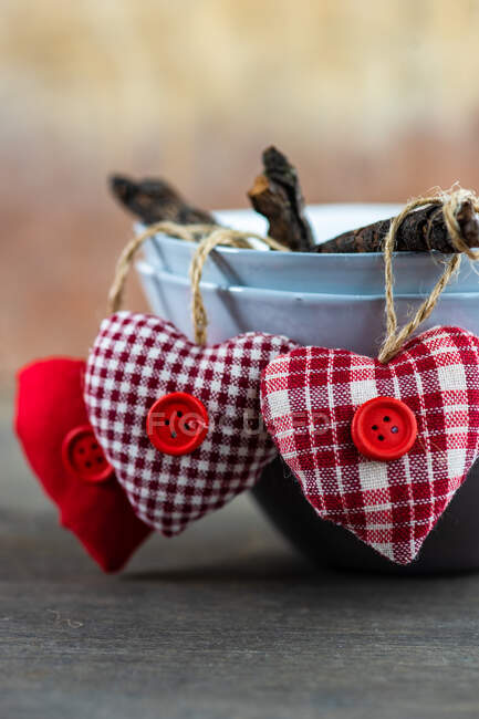 Red textile hearts hanging over the edge of  bowls — Stock Photo