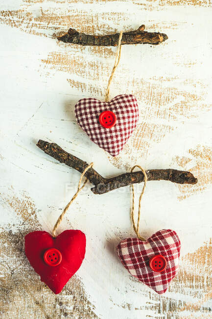 Decoraciones corazón textil rojo en palos de las mujeres — Stock Photo