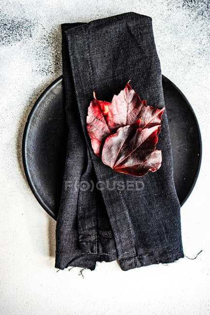 Autumnal place setting with a napkin and leaf decorations on a table — Stock Photo