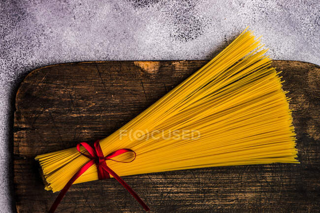 Bando de espaguete cru amarrado com uma fita em uma tábua de corte — Fotografia de Stock