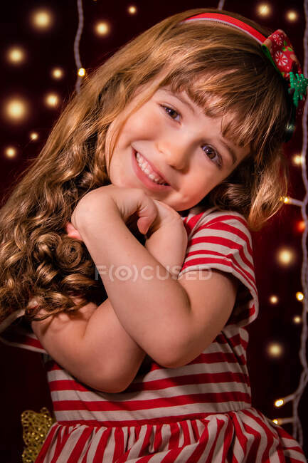 Retrato de una chica sonriente frente a las luces de Navidad - foto de stock