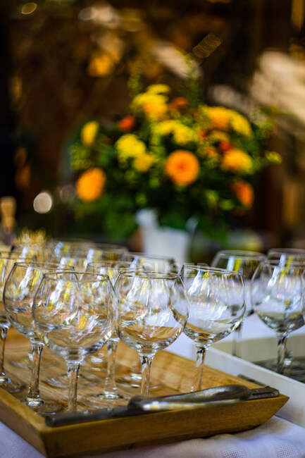 Close-up de copos de vinho em uma bandeja com flores no fundo — Fotografia de Stock
