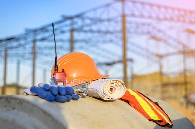 Reflective clothing, hard hat, gloves, walkie-talkie and construction plans on a building site, Thailand — Stock Photo
