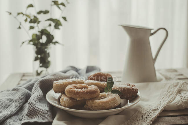 Тарелка самодельных пончиков на столе у окна — стоковое фото