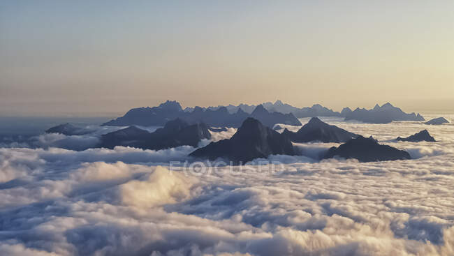 Picos de montaña surgiendo a través de la alfombra de nubes, Lofoten, Nordland, Noruega - foto de stock