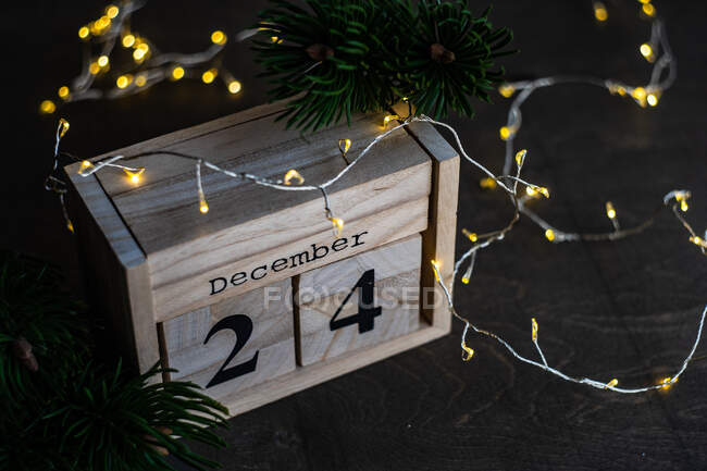 Деревянный календарь на Рождество со сказочными огнями и еловыми ветвями — стоковое фото