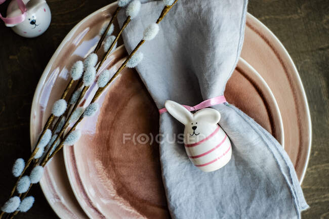 Luogo di impostazione per la cena di Pasqua festiva con piatto decorato con coniglietto pasquale rosa su sfondo rustico con spazio copia — Foto stock