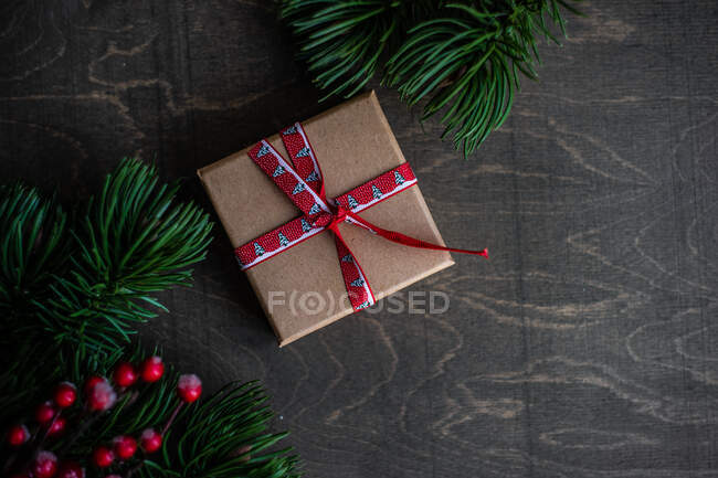 Presente de Natal agasalhado com ramos de abeto em uma mesa — Fotografia de Stock