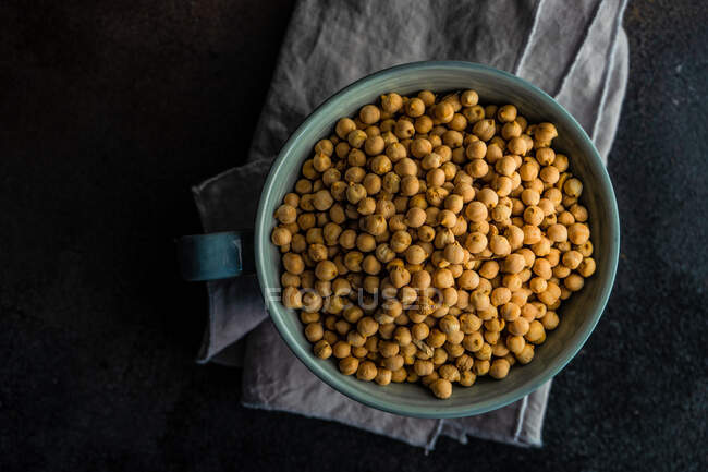 Ceramic bowl full of raw cheakpeas on rustic background with copy space — Stock Photo