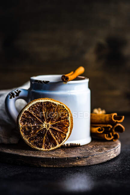 Mug of hot chocolate with cinnamon sticks and orange on rustic background with copy space — Stock Photo