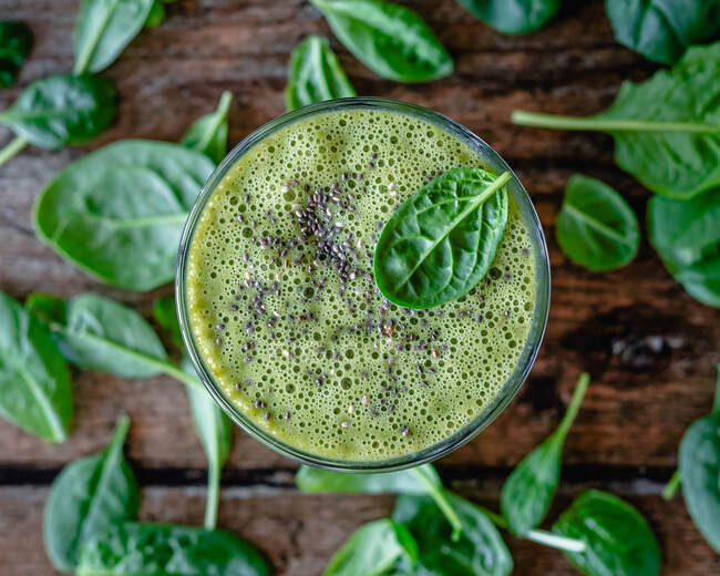 Overhead view of a green smoothie with chia seeds and spinach leaves — Stock Photo