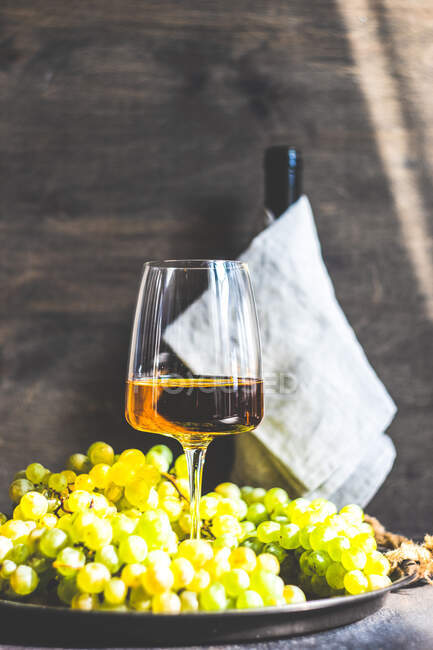 Glas georgischer Rkatsiteli-Wein im Glas und frische rohe Trauben auf rustikalem Tisch — Stockfoto