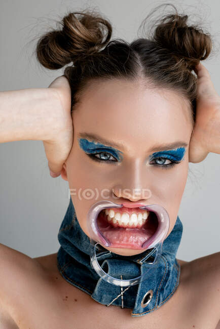 Retrato de una mujer que lleva un retractor bucal dental cubriéndose las orejas - foto de stock